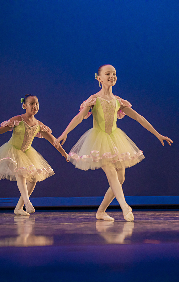 Young girl dancer in summer ballet dance camp on stage smiling as she pliés Young girl dancer in summer ballet dance camp on stage smiling as she pliés