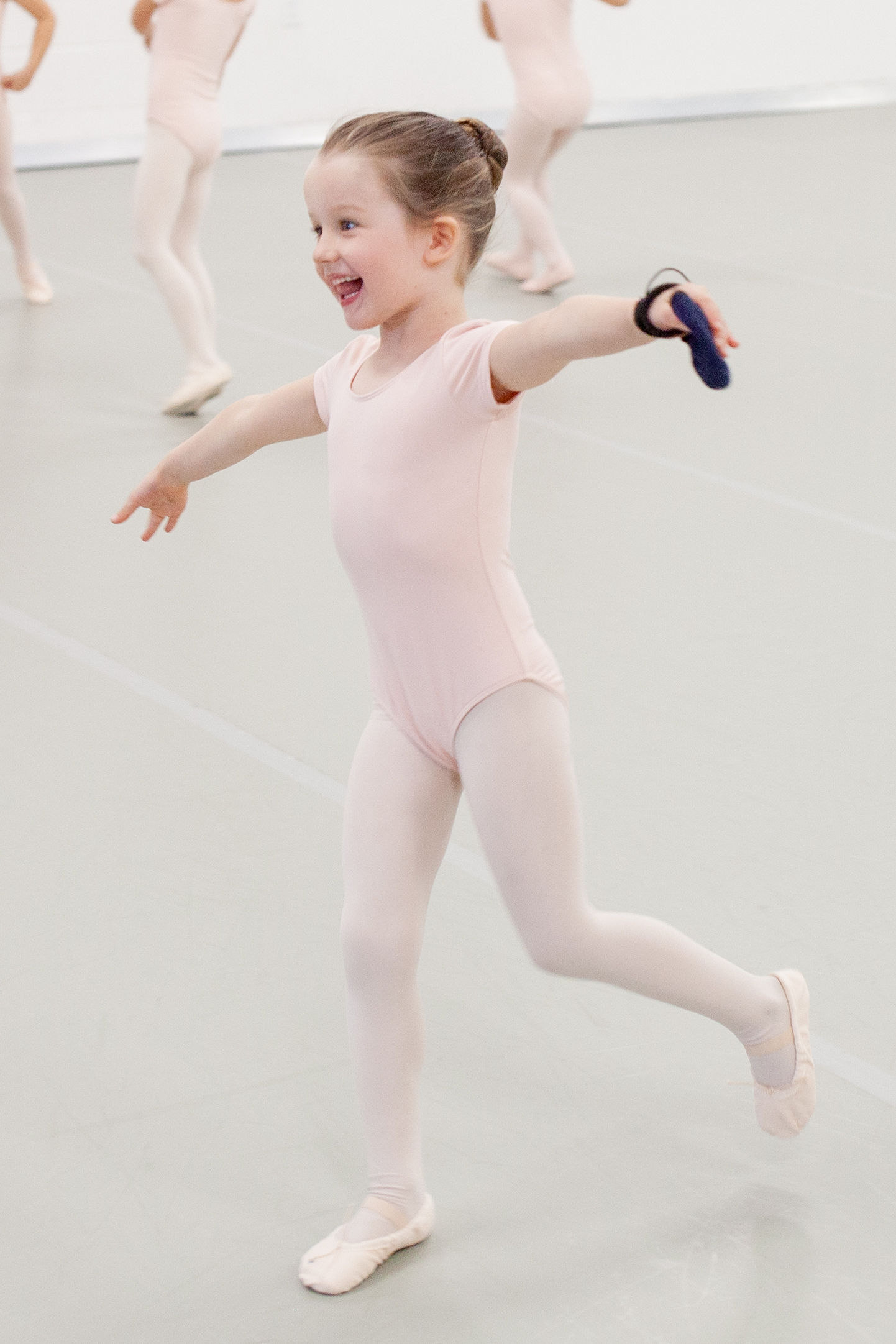 beginning ballet dancer in class practicing leaps across studio