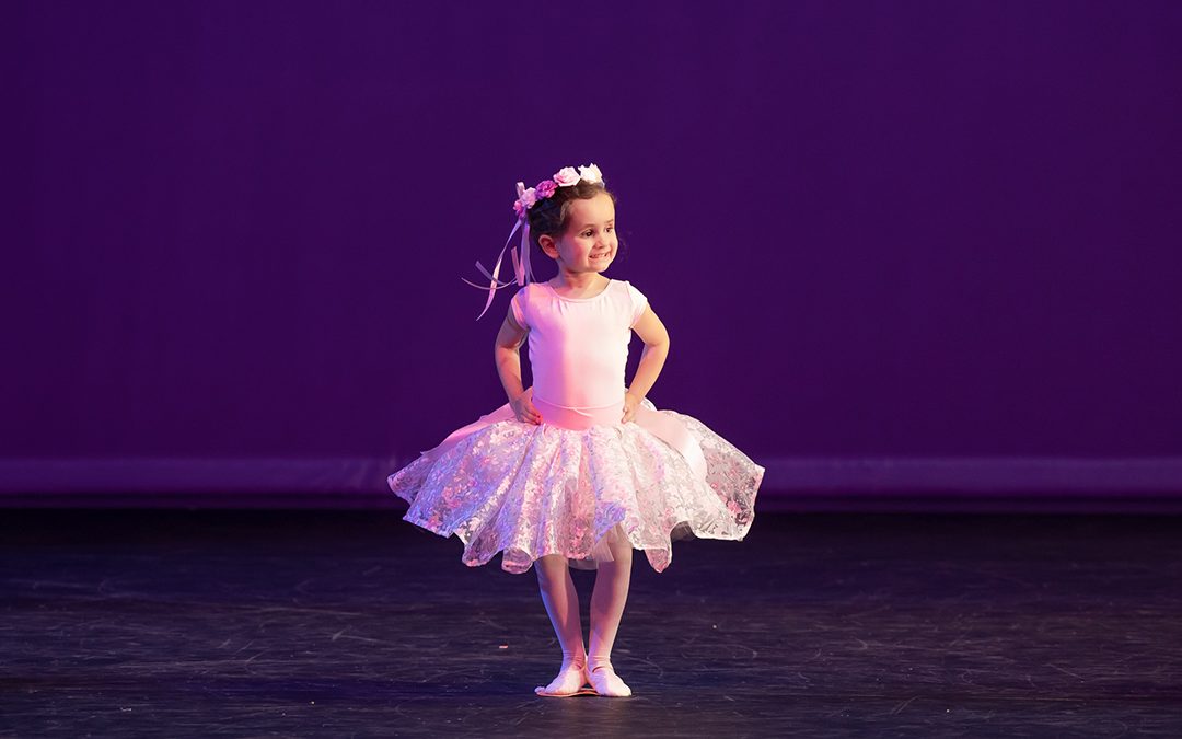 Young child in creative ballet on stage wearing tutu and flower crown